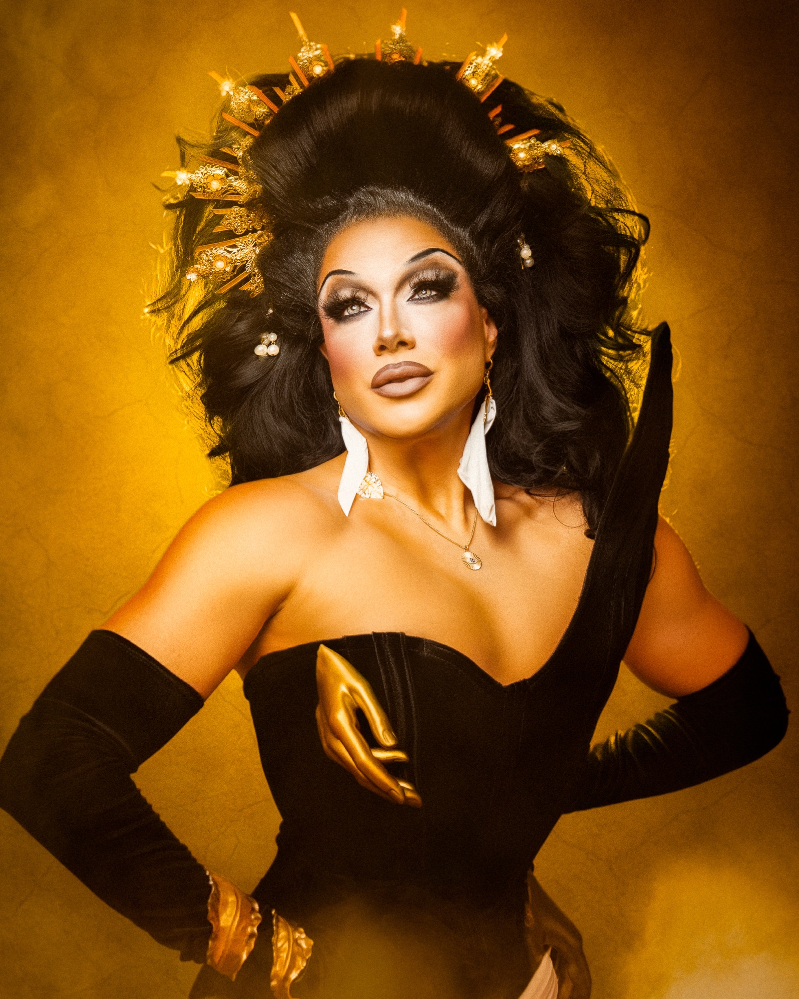 Close-up of Athena Dion wearing a gold crown against a golden backdrop