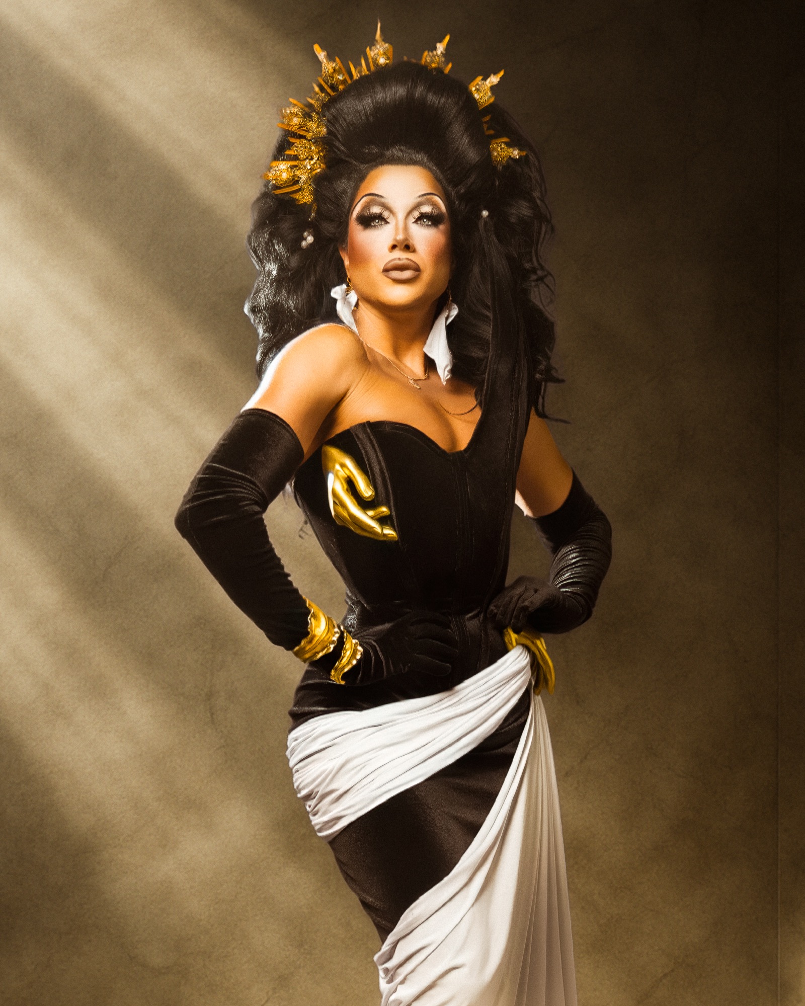 Athena Dion in a black and ivory gown with a sculptural gold crown